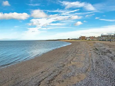a sandy beach with buildings in the background at Woodland Pod in Leadburn