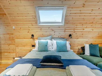 a bedroom with a large bed in a wooden wall at Woodland Pod in Leadburn