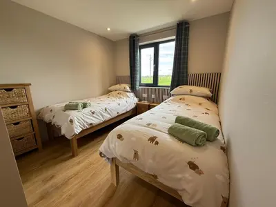 a bedroom with two beds and a window at Loganlea Lodge in Loanhead
