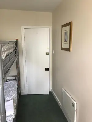 a room with a white door and a bunk bed at The Shorehouse in Brodick