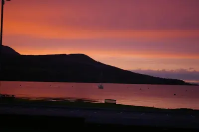 a sunset over a body of water with a mountain at The Shorehouse in Brodick