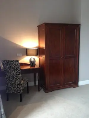 a desk with a lamp and a chair next to a cabinet at Creity Hall Guest House in Doune