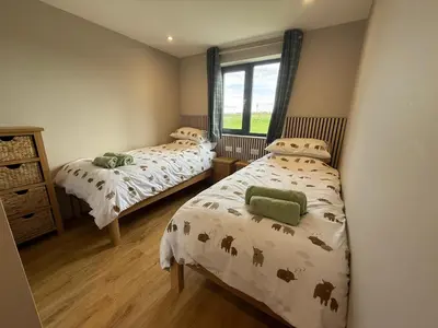 a bedroom with two beds and a window at Threipmuir Lodge in Loanhead