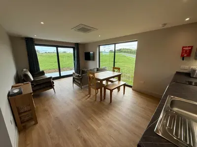 a kitchen and living room with a table and chairs at Threipmuir Lodge in Loanhead