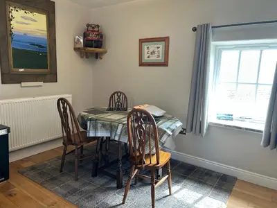 a dining room with a table and chairs and a window at Sanda View, Isle of Arran in Sliddery