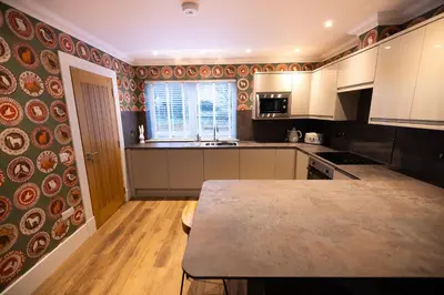 a kitchen with white cabinets and a table in it at Bracken Lodge in Comrie