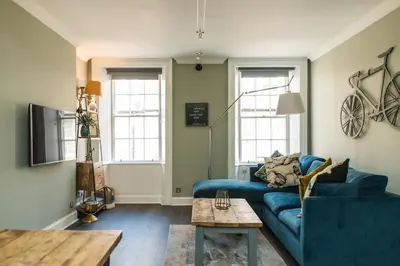a living room with a blue couch and a table at The Cobbled Rider in Edinburgh