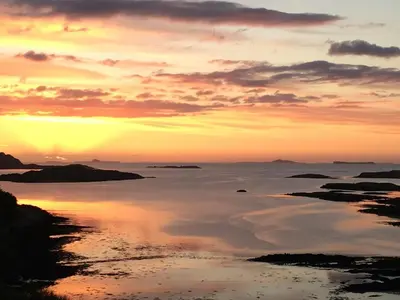 a sunset over a body of water with clouds at Cala Fearnadh Off-Grid cabin, Bunessan, Mull in Bunessan