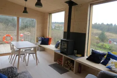 a living room with a table and a tv in a room at Cala Fearnadh Off-Grid cabin, Bunessan, Mull in Bunessan