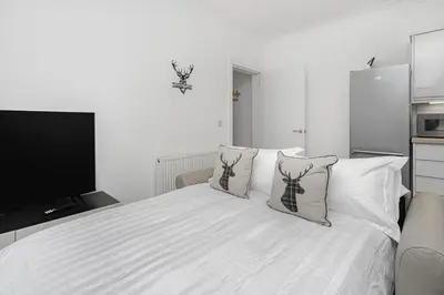 a bedroom with a white bed with pillows and a television at Coaledge Coorie - A wee find in Fife in Fordell