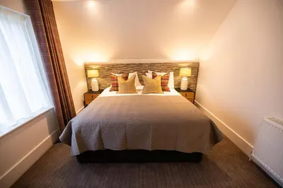 a bedroom with a large bed with yellow pillows at Heather Lodge in Comrie
