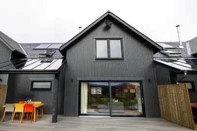 a black house with orange chairs and a table at Heather Lodge in Comrie