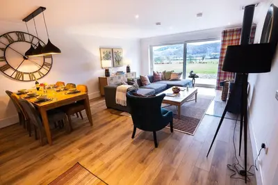 a living room with a table and a dining room at Thistle Lodge in Comrie