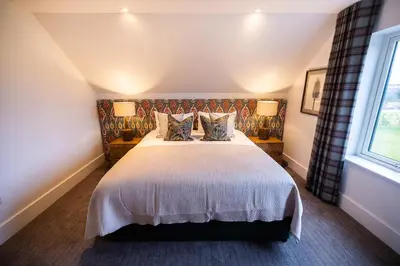 a bedroom with a large bed with two lamps at Thistle Lodge in Comrie