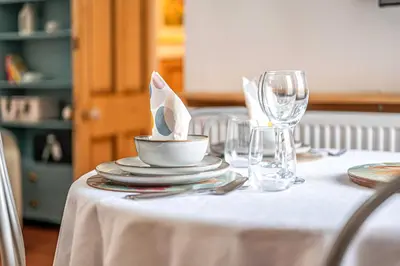 a table with a white table cloth with a bowl and glasses at Number Two Aberdour - Pretty Village nr Edinburgh in Aberdour