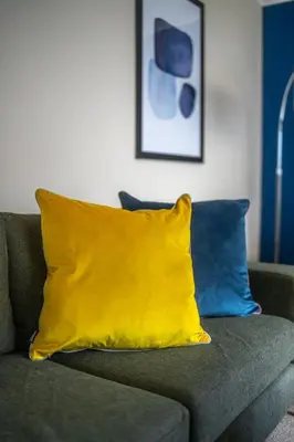 a yellow pillow on a couch with two blue pillows at Camps Rigg Place in Livingston