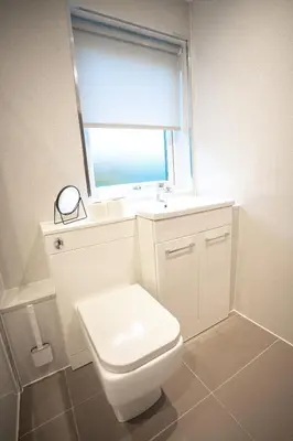 a white bathroom with a toilet and a window at Bonnie Apartment in Coatbridge