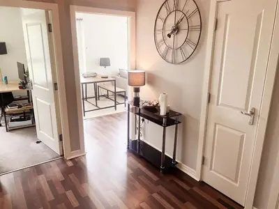 a room with a clock on the wall and a table at Modern Two Bed Glasgow Apartment with Free Parking in Glasgow