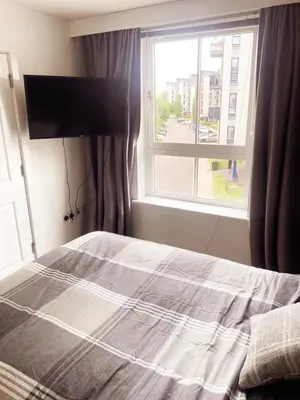a bedroom with a bed with a window and a flat screen tv at Modern Two Bed Glasgow Apartment with Free Parking in Glasgow