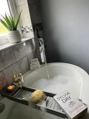 a bath tub filled with water and a glass of wine at Gellyburn Cottage in Kinross