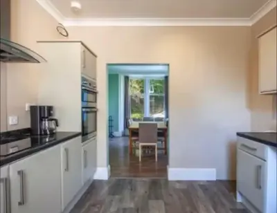 a kitchen with white cabinets and a dining room at Snug Loft Room, Room 5, Beautiful Connel near Oban in Connel