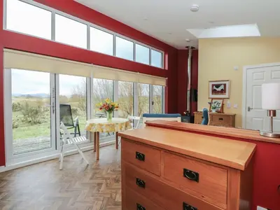 a kitchen with red walls and a dining room with a table at Tirlaggan Studio in Oban