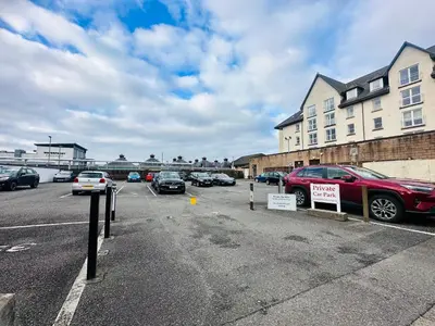 a parking lot with cars parked in front of a building at Kilmartin Court Apartments - No3 By The Sea & No2 With A View - free parking in Oban