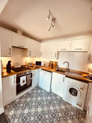 a kitchen with white cabinets and a sink and a dishwasher at Kilmartin Court Apartments - No3 By The Sea & No2 With A View - free parking in Oban