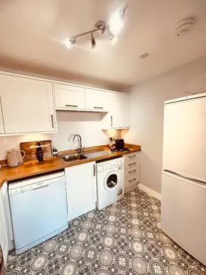 a kitchen with white cabinets and a sink and a dishwasher at Kilmartin Court Apartments - No3 By The Sea & No2 With A View - free parking in Oban