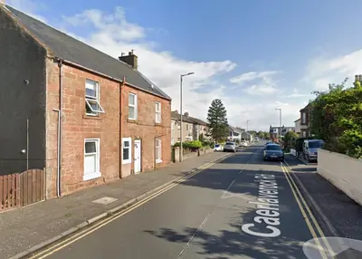 an empty street with cars parked on the side of the road at Apartment Caerlaverock Road in Prestwick