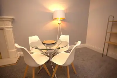 a dining room with a glass table and white chairs at Renovated West End Flat in Glasgow in Glasgow