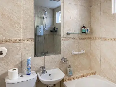 a bathroom with a shower and a toilet and a sink at Cosy Cottage in Lamlash