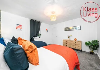 a bedroom with a bed with orange and blue pillows at Colt Apartment by Klass Living Coatbridge in Glenboig