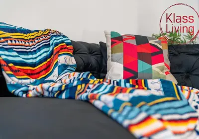 a pile of blankets and pillows on a couch at Orbiston House by Klass Living Bellshill in Bellshill