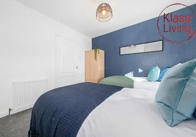 a bedroom with a bed with a blue accent wall at Orbiston House by Klass Living Bellshill in Bellshill