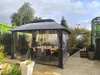 a black gazebo with a table in a garden at Rustic Harmony - Edinburgh Airport near, 8mi in Rosyth