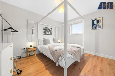 a white bedroom with a bed and a wooden floor at 3Bed Home Sleeps 6 w Private Parking in Dunfermline