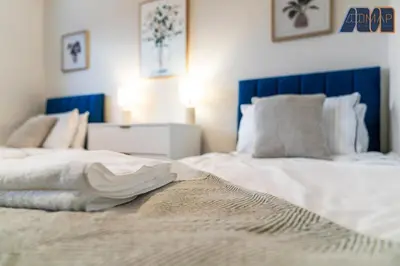 a large white bed with a blue headboard in a bedroom at 3Bed Home Sleeps 6 w Private Parking in Dunfermline