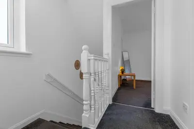 a hallway with a white staircase with a mirror at Vacant Nests The Grampian Free Wifi in Wishaw