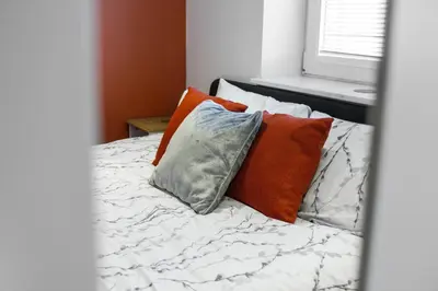 a bed with four pillows on it with a window at Slateford 2 Bedroom Apartment - Edinburgh in Edinburgh