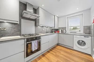 a kitchen with white cabinets and a washer and dryer at Slateford 2 Bedroom Apartment - Edinburgh in Edinburgh