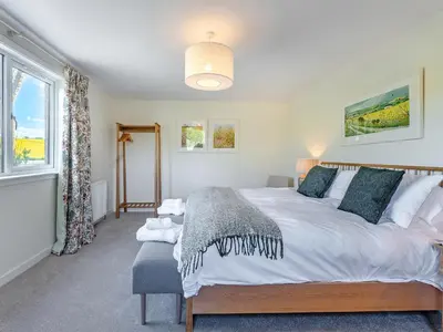 a bedroom with a large bed and a window at Newbigging Farm Cottage in Auchterarder