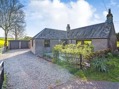 a brick house with a fence in front of it at Newbigging Farm Cottage in Auchterarder