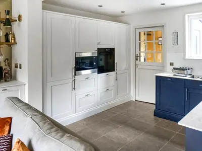 a kitchen with white cabinets and a blue island at Alt Na Blathaich in Coirantee