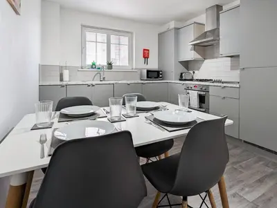 a white kitchen with a table and chairs in it at Pilmuir Apartment 3 bed 2 bath in Dunfermline