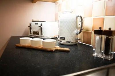 a counter top with a coffee maker and cups on it at Glasgow City - Large Stylish 2 Bed Flat in Unique Ibrox Location Walking Distance to Subway and Free On-Street Parking in Glasgow
