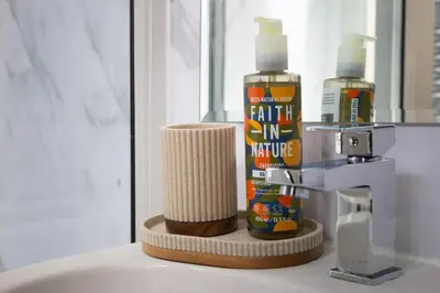 a bathroom counter with a bottle of hair oil and a mirror at Glasgow City - Large Stylish 2 Bed Flat in Unique Ibrox Location Walking Distance to Subway and Free On-Street Parking in Glasgow