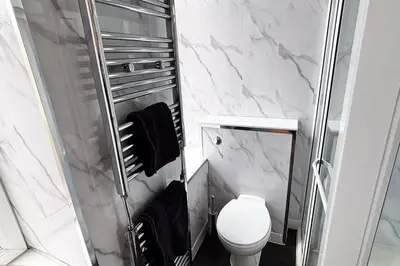 a white bathroom with a toilet and a shower at Glasgow City - Large Stylish 2 Bed Flat in Unique Ibrox Location Walking Distance to Subway and Free On-Street Parking in Glasgow