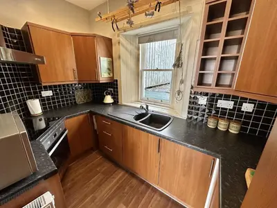 a kitchen with wooden cabinets and a sink and a window at Traditional Inveraray Cottage - Amazing Loch Views in Inveraray
