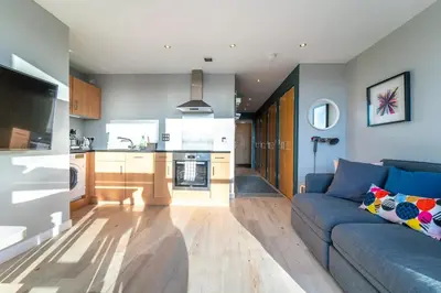 a living room with a blue couch and a kitchen at Stylish Studio Finnieston City Centre Free Parking in Glasgow
